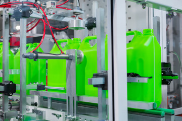 Empty green plastic jerrycans moving on conveyor belt of automatic pet blow molding machine at...