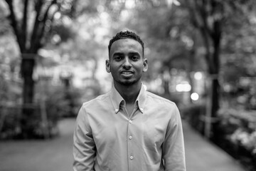 Black and white portrait of handsome black young African businessman outdoors in city