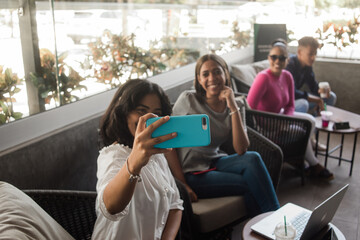 Grupo de amigas tomando una selfie sentados, celular en primer plano