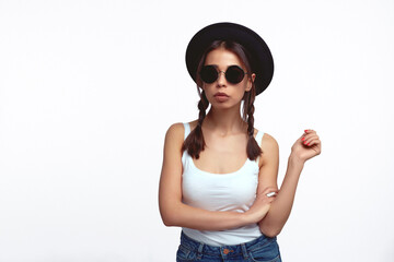 Stylish young girl in white shirt with sunglasses posing over white wall