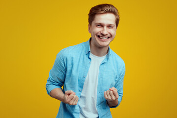 Lucky young man isolated over yellow background shows yes gesture 