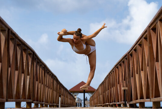 Flexible female circus Artist keep balance in split on the bridge. Healthy lifestyle, yoga and flexibility concept 