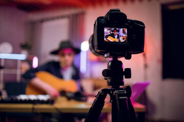 Modern digital camera with handsome musician on screen that playing guitar. Young stylish man...