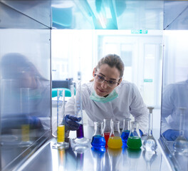 Young female scientist monitoring experiment with liquids in lab