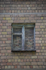 In the center of the brick wall there is an old window covered with brickwork, walled up with bricks and cement