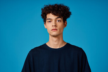 Fototapeta na wymiar guy in black t-shirt with curly hair blue background