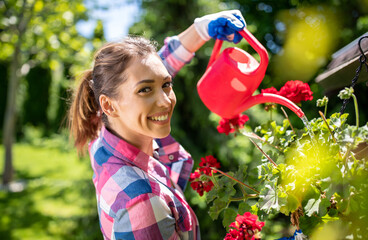 Girl watering flower in garden from can - obrazy, fototapety, plakaty