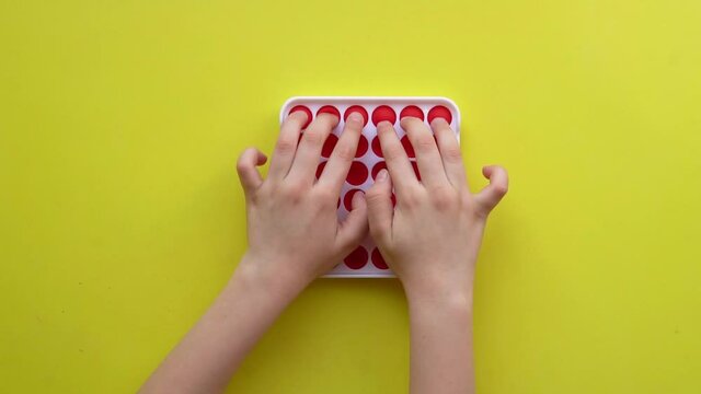 Popit antistress toy for children entertainment on a yellow background playing a child top view in colored fijit simple dimple popit yellow game play, anti kids pop popular rt, relax kid. Iew fine