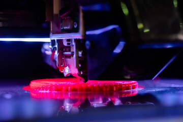 Print head of three dimensional printer machine printing flat red plastic model at modern...