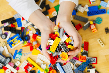 Close up of child's hands playing with colorful plastic bricks at the table. Development of fine motor skills in children, favorable for the development of brain activity. learning Developing toys