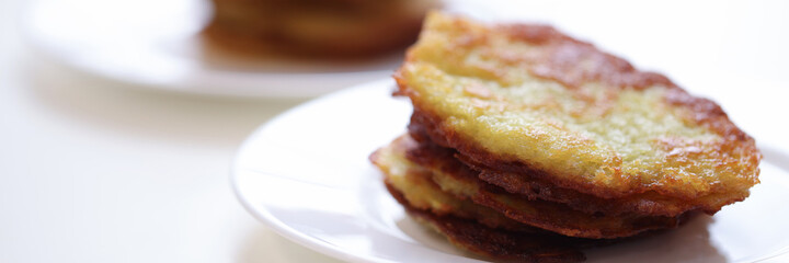 Potato latkes lying on white plate in cafe closeup