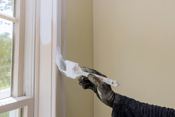 Hand of worker with gloves in the painting window molding trim