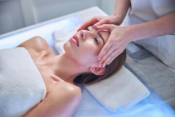 Obraz na płótnie Canvas Elegant adorable Caucasian woman getting face massage in spa center