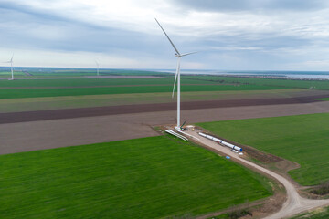 Wind turbine on a green field against a blue sky with clouds.