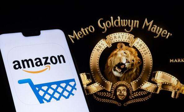 Amazon app logo seen on the smartphone and blurred Metro Goldwyn Mayer logo on the laptop. Stafford, United Kingdom, May 27, 2021.