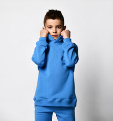 Clothes for schoolchildren. Studio portrait of a little boy in a trendy blue sports suit on a white...