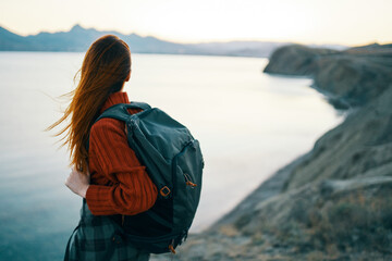 woman in red sweater with backpack and travel tourism sea mountains