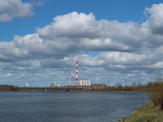 White clouds on blue sky and red striped chimney