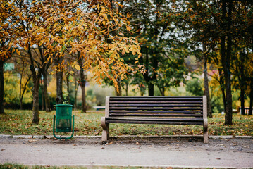 An urn next to an empty park bench.