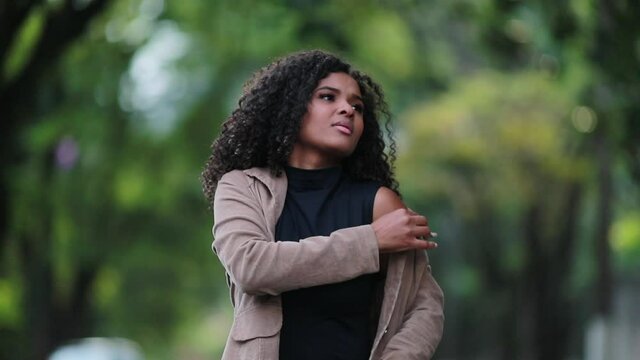 Black woman putting jacket outside. Elegant African girl wearing jacket