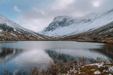 Mountain lake with reflections on the backgrond of a foggy snow -capped mountains, Kola Peninsula
