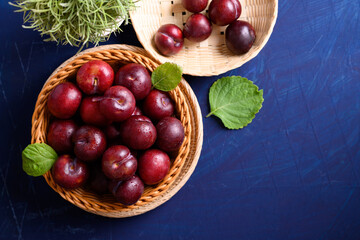 Fresh Japanese or Chinese plum fruit in bamboo basket on blue background, Top view