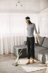 Fototapeta premium Woman vacuuming mat at home in a good mood