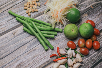 Papaya salad (Som Tam) ingredients on wooden table background.The famous local Thai street food dish with the taste of hot and spicy.