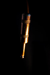 Macro Closeup of Vertical Worn Out Metal Quarter Inch Phone Jack Isolated on Black Background with Orange Lighting