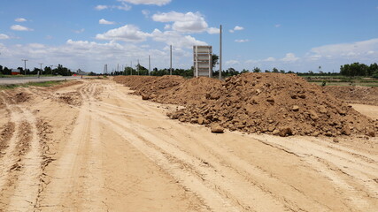 A pile of dirt on the highway. Lots of dirt mounds on the highway construction site with sky as a...