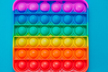 Rainbow sensory fidget isolated on blue background. New trendy silicone toy. Push pop bubble Silicone fidget toys.