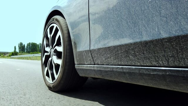 Low angle side view of sport car's tires speeding on the empty rural road