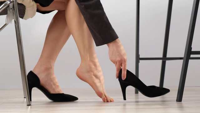 The woman takes off her shoe and massages her tired foot