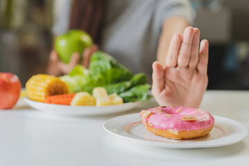Diet, Dieting young asian woman or girl use hand push out, deny sweet donut and choose green apple, salad vegetables, eat food for good healthy, health when hungry. Close up female weight loss person.