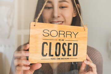 Smiling asian young owner retail, coffee shop woman turning sign board to closed after finished...