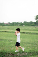 happy little Asian boy run on the field