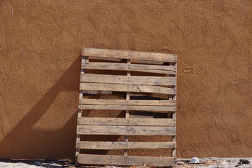 An old used wooden pallet leaning against a building wall