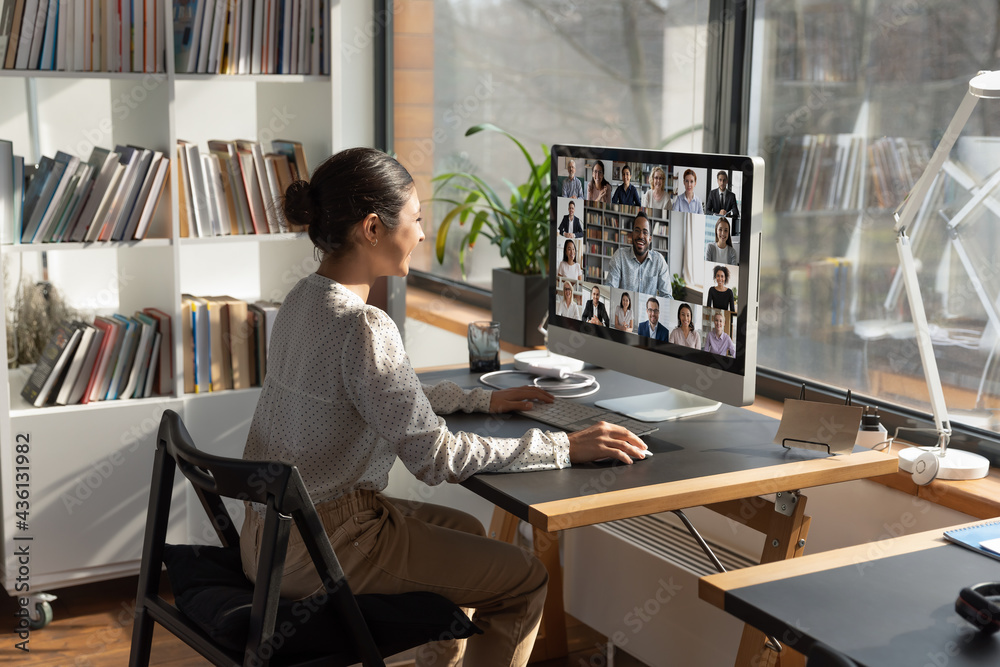 Wall mural rear view indian businesswoman involved in internet meeting with colleagues, group video call, diver