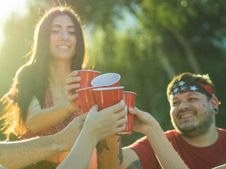 Group of young people clinking plastic red cups at a party