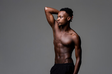 Fototapeta na wymiar Shirtless African man posing with one arm up isolated gray on studio background
