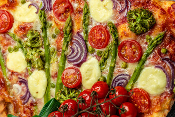 Close up asparagus tart. pie filled with fresh asparagus, sweet peas, mozzarella and cherry tomatoes. Vegan food recipe background