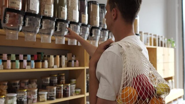 Man in a mindful consumption store without packaging with pasta, nuts or grains in a store without plastic waste. Low-waste lifestyle. Sustainable ecological lifestyle. Eco shop