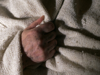 Dirty hand of poor person wrapped in a blanket