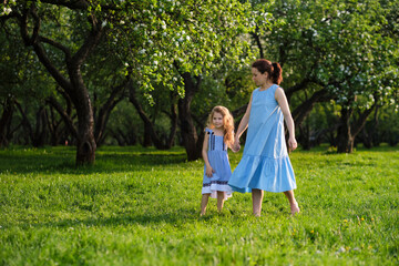 Fototapeta premium nature scene with family outdoor lifestyle. Mother and little daughter playing together in a park. Happy family concept. Happiness and harmony in family life.