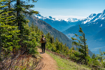 Person hiking on a trail on Elk Mountain, British Columbia on a sunny day with snow capped mountains in the background