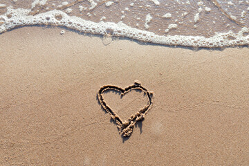 One Heart Drawn in the Sand on a Beach.soft wave of the sea.Romantic love. true love.Beige beach