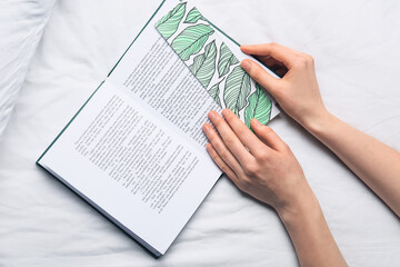 Woman with cute bookmark and book on bed - obrazy, fototapety, plakaty