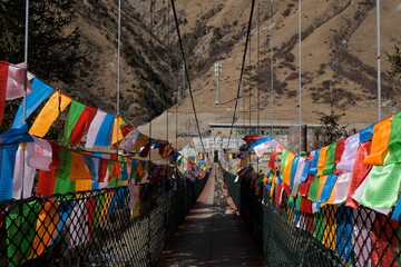 colorful Buddhist prayer flags on both sides of the bridge with Mountain background
