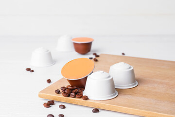 Board with coffee capsules on white table