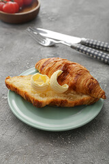 Tasty croissant with butter on grunge background